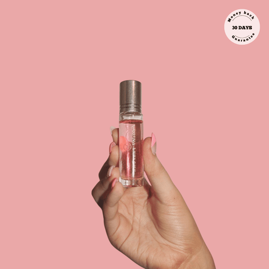PheroPerfumes roll-on perfume bottle held against a pink background